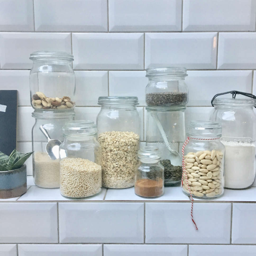 Collection of glass jars on kitchen shelf.